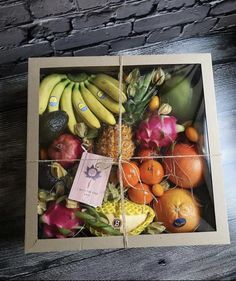 a box filled with assorted fruit on top of a wooden table