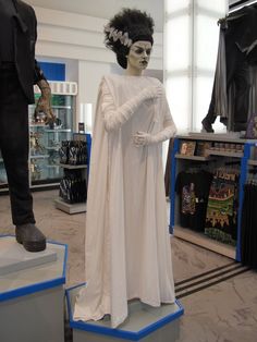 a statue of a woman in white is on display at a store with other mannequins