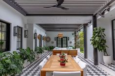 an outdoor dining area with black and white checkered flooring, potted plants, and ceiling fan