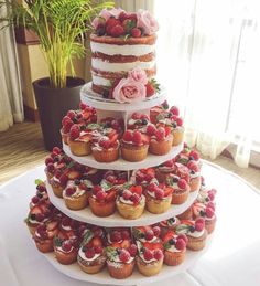 a triple layer cake with strawberries and cupcakes