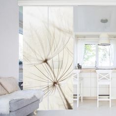 an open kitchen and living room area with white furniture in the background, along with a large dandelion wall mural