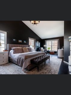 a large bedroom with black walls and white furniture, including a king size bed in the center