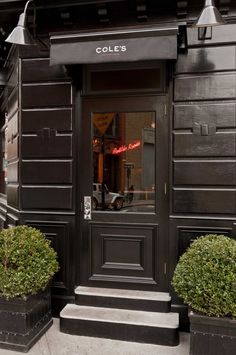 the entrance to cole's restaurant with two large planters on either side of the door