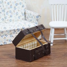 an open suitcase sitting on top of a wooden floor next to a chair and table