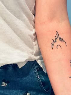 a woman's arm with a tattoo on it that has mountains in the background