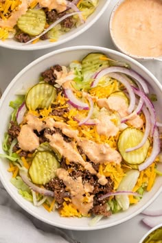 two white bowls filled with taco salad and dressing on top of a tablecloth