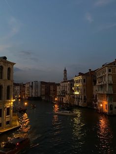 a river that has some boats on it and buildings in the background at night time