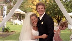 a man and woman are standing under a gazebo smiling at the camera with their arms around each other