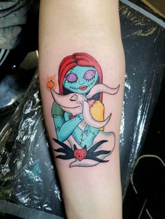 a woman with a tattoo on her arm holding an orange and blue heart in her hand