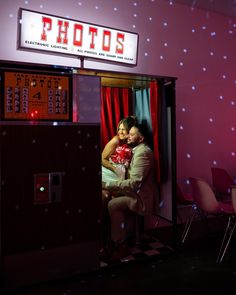 a man and woman hugging in front of a photo booth