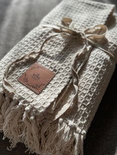 a white blanket wrapped in tassels with a tag on it's side