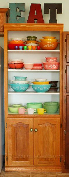 a wooden cabinet filled with lots of bowls and plates on top of it's shelves