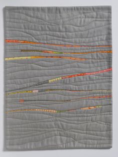 a piece of quilted material with different colored lines on the fabric, and white background