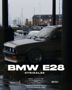 the bmw e23 is parked in front of some boats