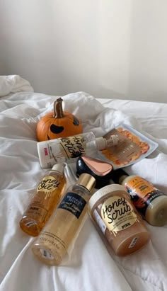 bottles of booze sitting on top of a bed next to an orange and white pumpkin