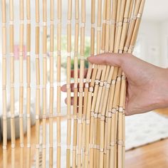 a hand is holding the top of a bamboo curtain