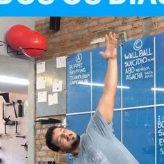 a man in grey shirt doing a handstand on wall with blue and white background