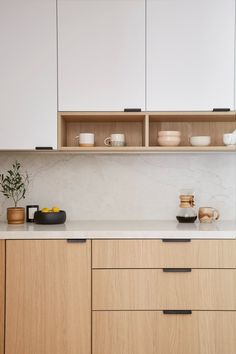 a kitchen with wooden cabinets and white marble counter tops, along with bowls on the counters