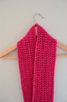 a pink scarf hanging on a wooden hanger