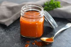 a jar filled with sauce sitting on top of a table next to a small spoon