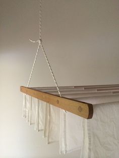 a wooden beam hanging from the ceiling with white curtains on it's sides and a chain attached to one end