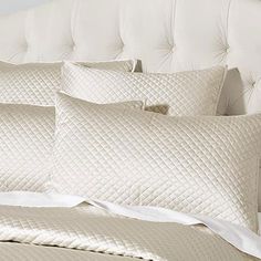 a bed with white sheets and pillows on it