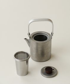 a tea kettle and cup on a white surface