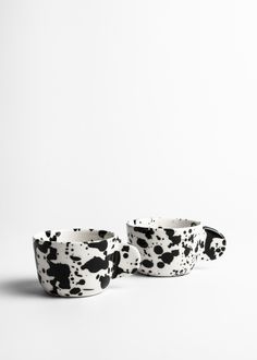 two black and white bowls sitting next to each other on top of a white surface