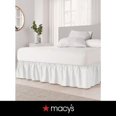 a bed with white sheets and ruffled bedskirt on it's side