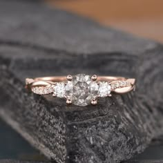 three stone diamond ring sitting on top of a rock