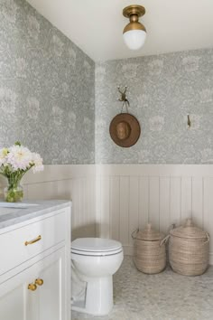 a white toilet sitting in a bathroom next to two baskets filled with flowers on top of a counter