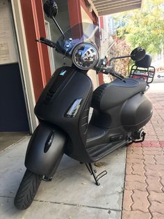 a black scooter parked on the sidewalk next to a building