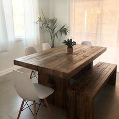 a wooden table with two white chairs and a potted plant