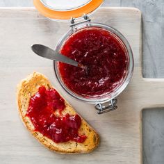 a piece of bread with jam on it next to a bowl of jelly and a spoon