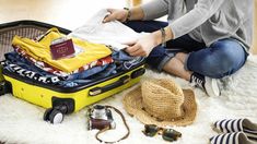 a woman sitting on the floor next to her suitcase filled with clothes and other items