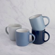 three blue and white coffee mugs stacked on top of each other in front of a marble background