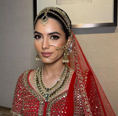 a woman in a red and gold bridal outfit with an elaborate nose ring on her head