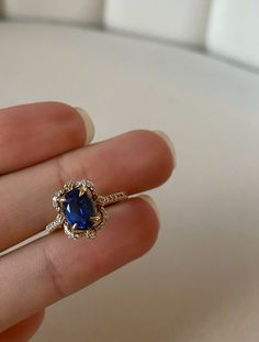 a woman's hand holding a ring with a blue stone