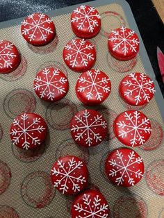 red frosted cookies with white snowflakes sitting on a cookie sheet in the shape of hearts