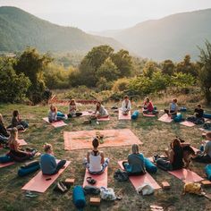 a group of people sitting on top of pink mats in the middle of a field