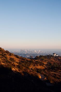 a bench on the side of a hill with a view of a city in the distance