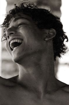 black and white photograph of a shirtless young man with his mouth open wide open