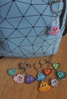 several keychains with different designs on them sitting next to a handbag and purse