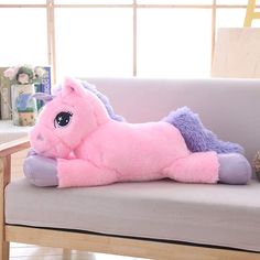 a pink stuffed horse laying on top of a couch