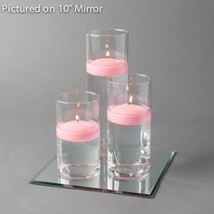 three candles are placed on a mirrored surface