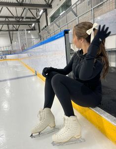 a woman sitting on the edge of an ice rink