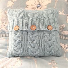 a blue knitted pillow with buttons on it