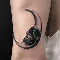 a black and white tattoo of a skull on the arm with a crescent moon behind it