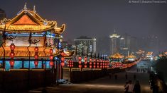 people are walking along a path with lanterns lit up in the night sky behind them