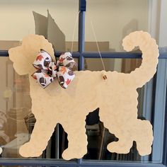 a paper dog with a bow hanging from it's side on a window sill